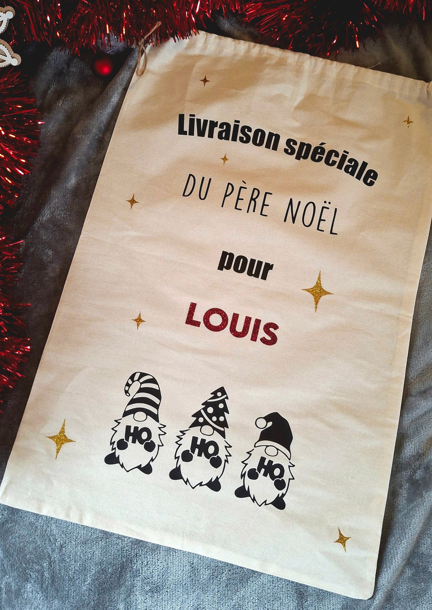 Détail de la personnalisation du prénom sur hotte de Noël – gnomes festifs rouges et gris
